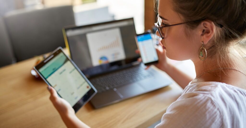 Lancaster SMB professional managing work tasks across multiple personal devices with a laptop, phone, and tablet.