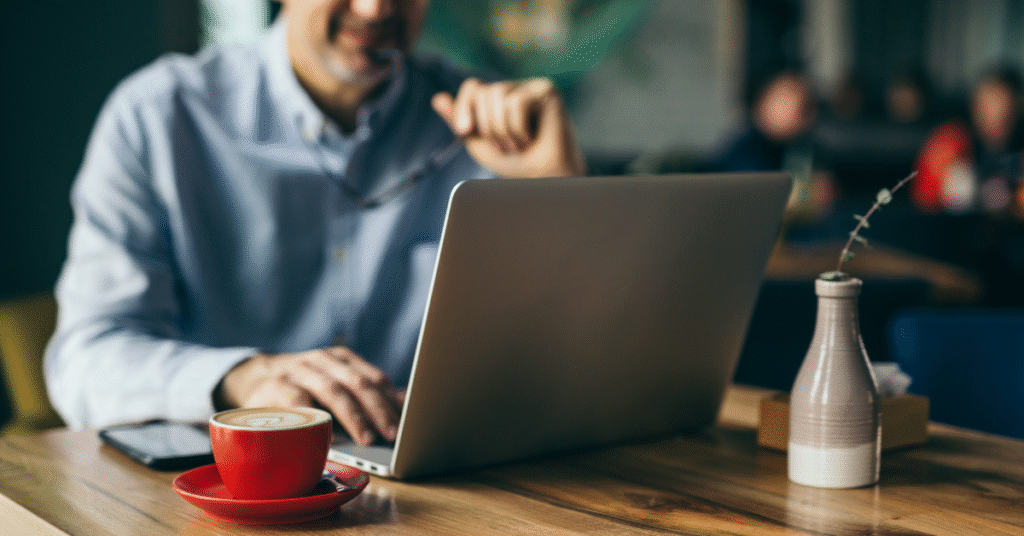 Person shopping online during the holidays with laptop and coffee, staying cyber-safe using holiday cybersecurity tips.