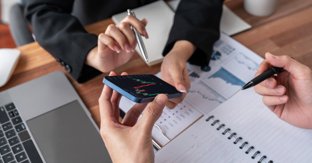 Financial leaders reviewing performance data on a mobile device as part of company risk management planning